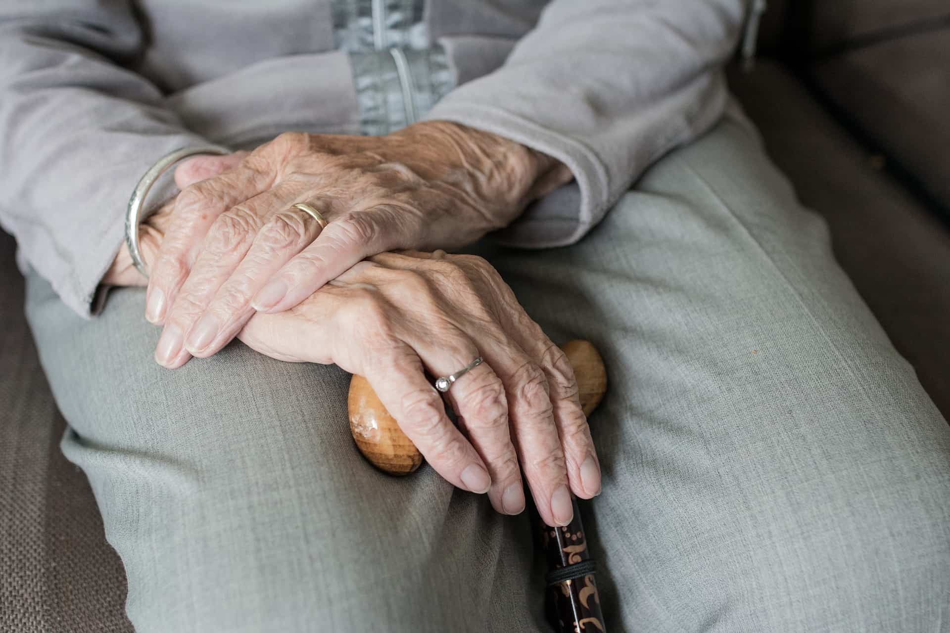 Elderly hands holding a cane, symbolizing aging and healthcare.