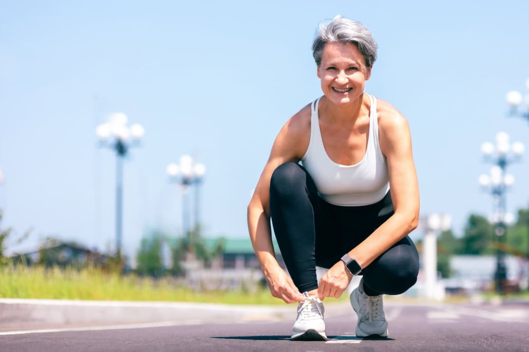 Energetic,Mature,Woman,In,Sportswear,Tying,Her,Shoelaces,Before,A senior woman tying her shoelace on the track