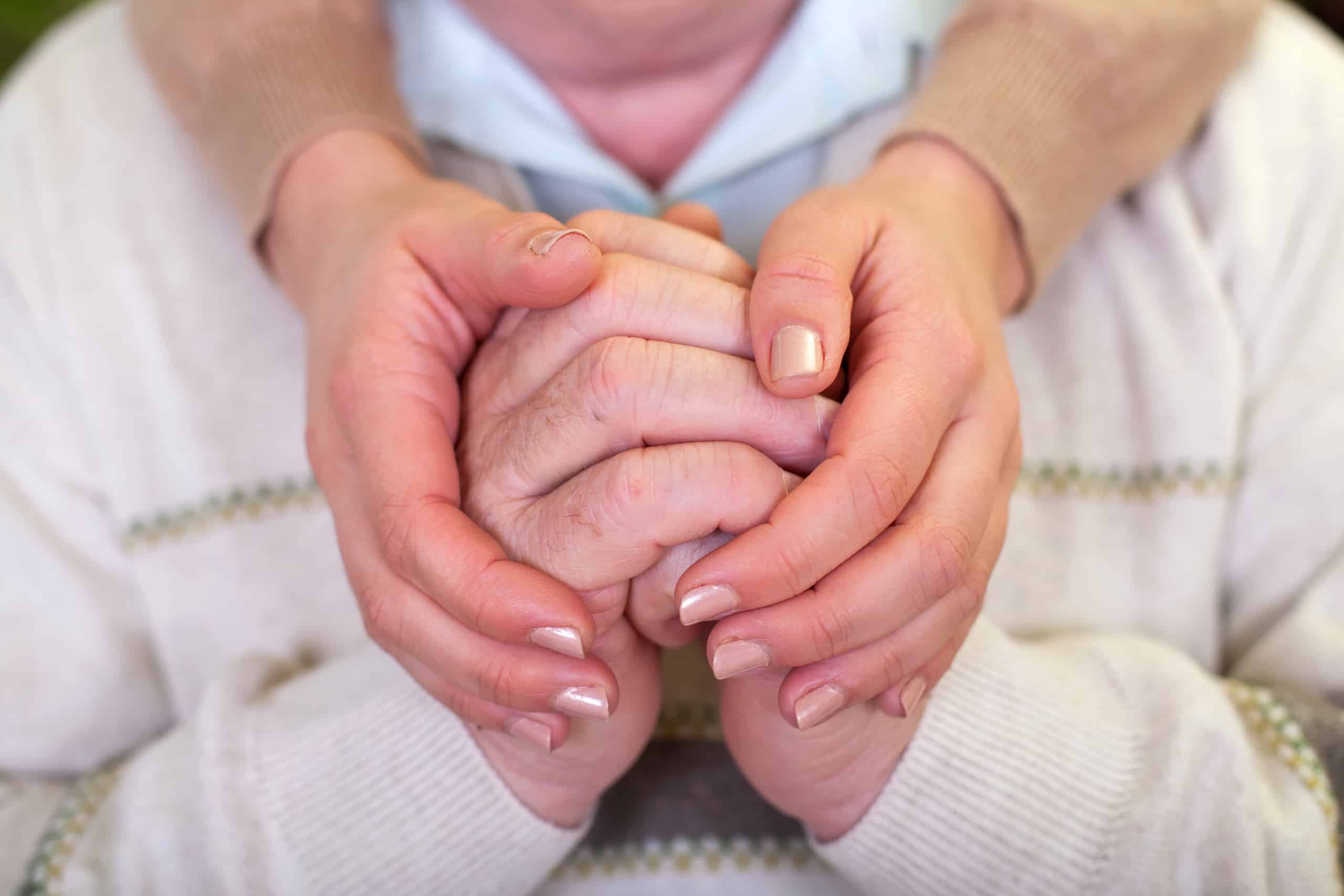 Aging hands being held gently, highlighting stem cell therapy support for elder health.